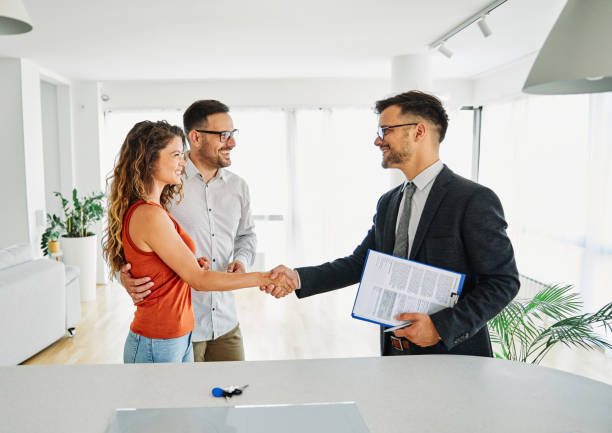 real estate agent with couple shaking hands closing a deal